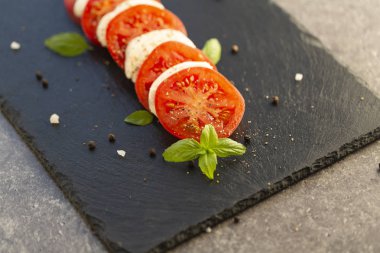 Mozzarella ve domates karanlık bir plaka üzerinde taze İtalyan Caprese salatası