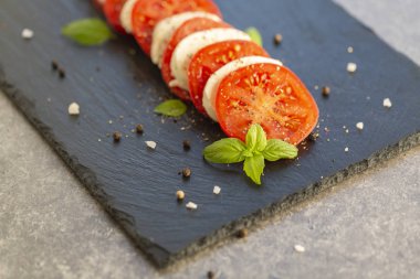 Mozzarella ve domates karanlık bir plaka üzerinde taze İtalyan Caprese salatası