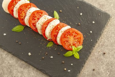 Mozzarella ve domates karanlık bir plaka üzerinde taze İtalyan Caprese salatası