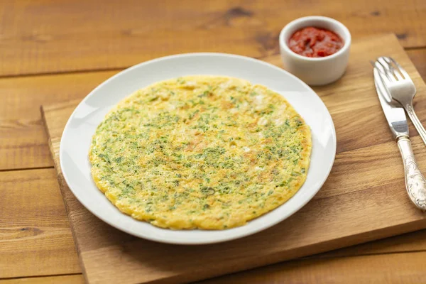 Otlar ile lezzetli omlet. Kahvaltıda omlet. Rendelenmiş peynir ve otlar ile omlet. Kahvaltı için yumurta çanak.
