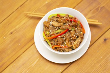 Tavuk, sebze ve susam ile Asya Erişte. Rustik ahşap arka plan. Yemek çubukları. Yakın çekim. Asya tarzı yemek