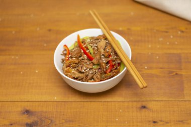 Tavuk, sebze ve susam ile Asya Erişte. Rustik ahşap arka plan. Yemek çubukları. Yakın çekim. Asya tarzı yemek