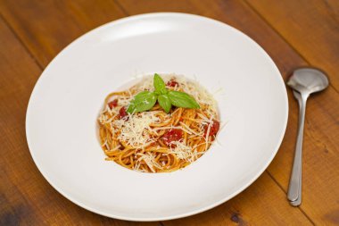 Tabak lezzetli İtalyan spagetti makarna ile taze fesleğen yaprakları, etli, domates sos, sebze ve parmesan peyniri rendesi