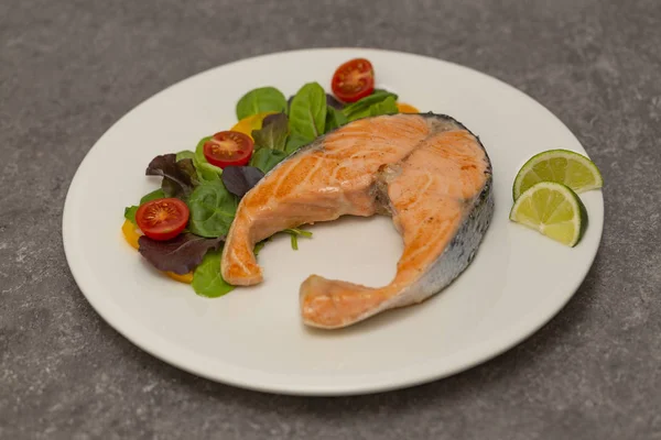 Salmon steak dinner with herbs and tomatoes.