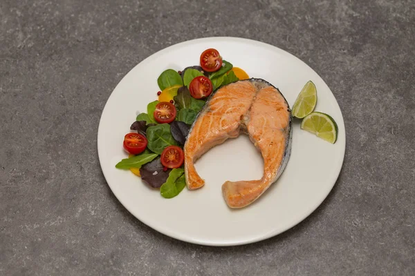 Salmon steak dinner with herbs and tomatoes.