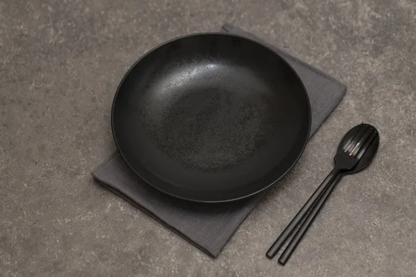 灰色石桌上的黑色盘子 餐具和餐巾纸 顶视图 — 图库照片