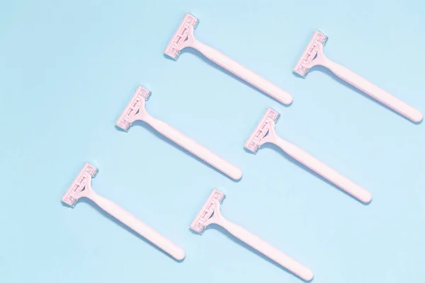 Pink female razors isolated on the blue background. Set of razors on blue background. Pink women\'s disposable razors . Hygiene skin body care concept. Hair removal.