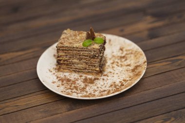 Çocuk oyuncağı Napoleon beyaz tabakta. Rus yemekleri, katmanlı pasta çikolatalı krema ile görünümü kapatın