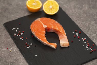 Baharatlar ve limon siyah arduvaz tabakta taze somon biftek