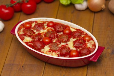 Ahşap bir masa üzerinde bir pişirme çanağı domates soslu köfte. Seçici odak