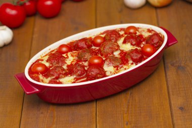 Ahşap bir masa üzerinde bir pişirme çanağı domates soslu köfte. Seçici odak