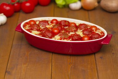 Ahşap bir masa üzerinde bir pişirme çanağı domates soslu köfte. Seçici odak