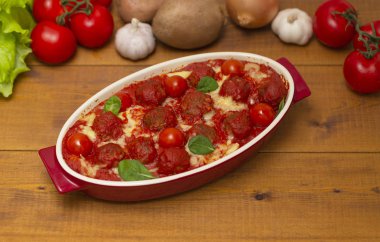 Ahşap bir masa üzerinde bir pişirme çanağı domates soslu köfte. Seçici odak