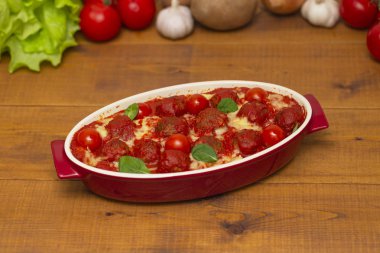 Ahşap bir masa üzerinde bir pişirme çanağı domates soslu köfte. Seçici odak