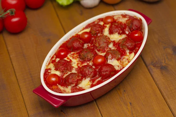 Ahşap bir masa üzerinde bir pişirme çanağı domates soslu köfte. Seçici odak