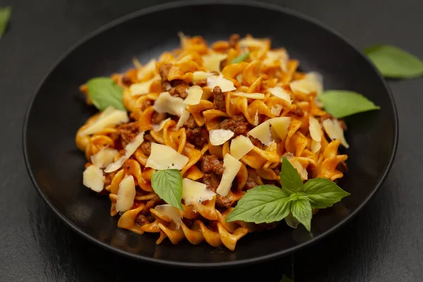 Domates soslu lezzetli iştah açıcı klasik İtalyan Düdük makarna peynir parmesan, sığır eti ve fesleğen masada siyah kase. 