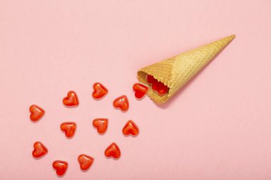 Gözleme koni ile pembe bir arka plan üzerinde kırmızı kalpler. Üstten görünüm. Aşk ya da Sevgililer günü kavramı. Üstten görünüm, düz yatıyordu