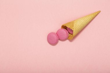 Dondurma waffle koni macarons üzerinde pembe bir arka plan ile. Şeker renkli ve pastel renkler. Sevgililer günü tatlı ve romantik an için kavram. Şekerli tatlı. Üstten görünüm.