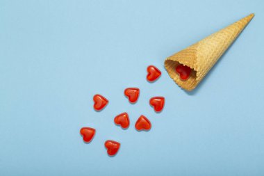 Gözleme koni ve mavi bir arka plan üzerinde küçük kırmızı kalpler. Romantik Sevgililer günü, tatil, parti, düğün için arka plan aşk. Düz yatıyordu.