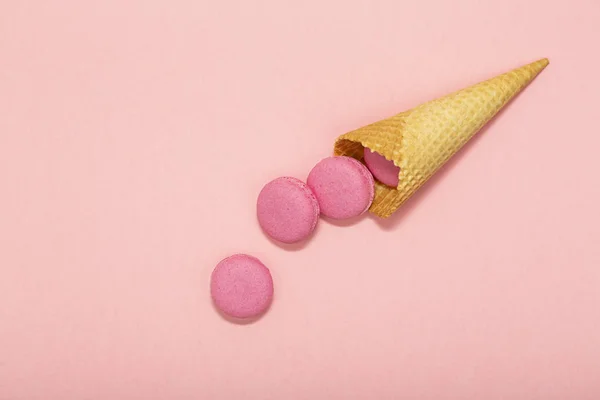 Dondurma waffle koni macarons üzerinde pembe bir arka plan ile. Şeker renkli ve pastel renkler. Sevgililer günü tatlı ve romantik an için kavram. Şekerli tatlı. Üstten görünüm.