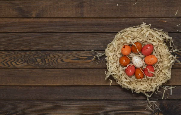 Yuvada ahşap arka plan üzerinde renkli Paskalya yumurtası. Kopya alanı ile üstten görünüm