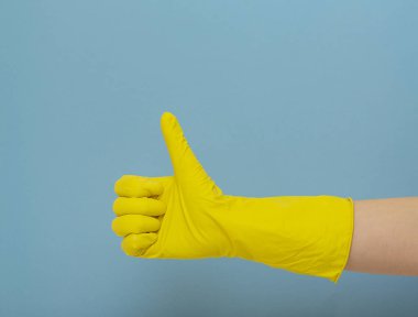 El ile sarı lastik eldiven. Üzerinde mavi arka plan temizleme sarı lastik eldiven. Temizlik kavramı.