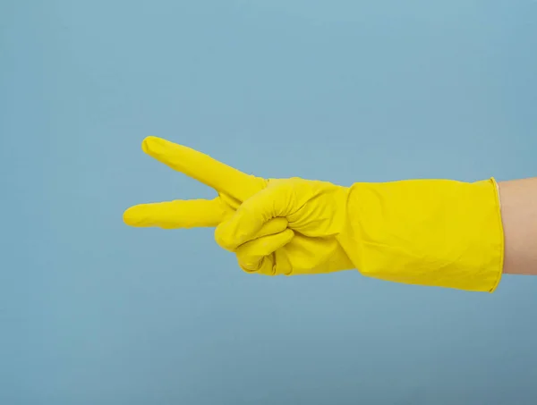 Hand with yellow rubber gloves. Yellow rubber gloves for cleaning on blue background. Cleaning concept.