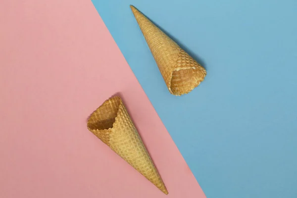 Ice cream waffle cones on pastel pink and blue background. Waffle ice cream cone. Top view. Flat lay. Modern minimal composition