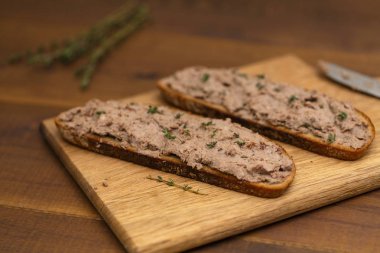 Ev yapımı tavuk karaciğer pate ekmek üzerine ahşap arka plan üzerinde. Lezzetli kahvaltı.