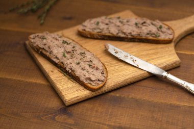Ev yapımı tavuk karaciğer pate ekmek üzerine ahşap arka plan üzerinde. Lezzetli kahvaltı.