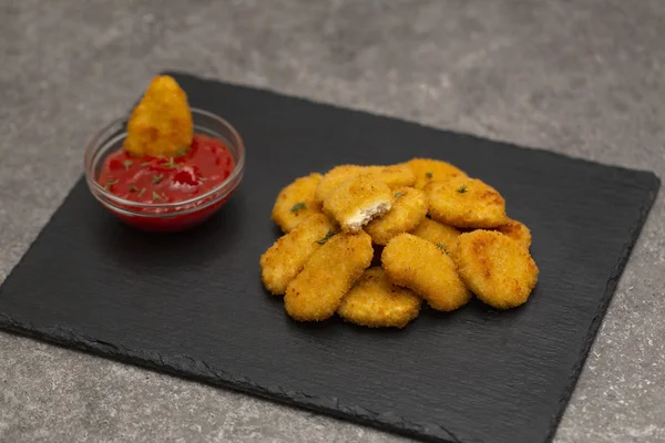 stock image Fried crispy chicken nuggets with ketchup on black board.