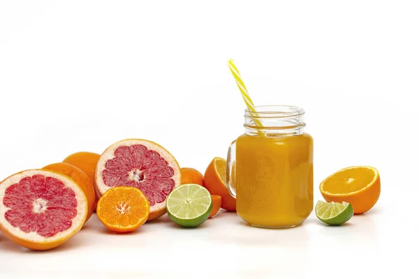 Freshly blended yellow and orange fruit smoothie in glass jar. Glass jar mugs with orange health smoothie, lime, grapefruit, lemon, tangerine. Selective focus. Copy space. Vegetarian food concept.