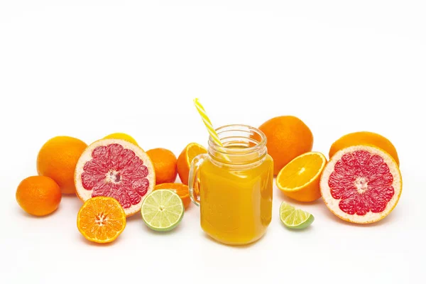 Freshly blended yellow and orange fruit smoothie in glass jar. Glass jar mugs with orange health smoothie, lime, grapefruit, lemon, tangerine. Selective focus. Copy space. Vegetarian food concept.