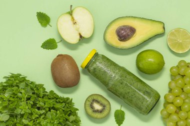 Şişe yeşil arka plan, üstten görünüm üzerinde renkli yeşil smoothie. Kahvaltı ve yemek için sağlıklı gıda.