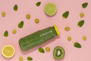 Şişe pembe arka plan, üstten görünüm üzerinde renkli yeşil smoothie. 