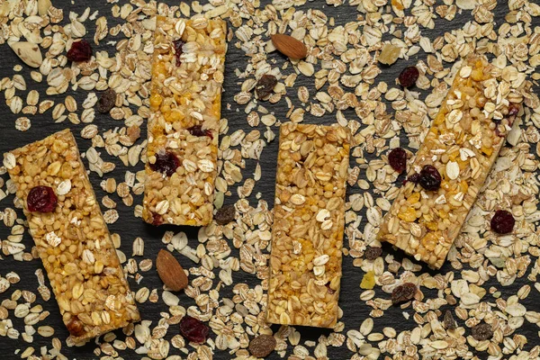 Granola bar. Healthy sweet dessert snack. Cereal granola bar with nuts, fruit and berries on a black stone table. Top view.