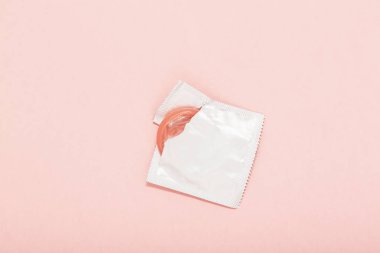 Pembe pembe bir arka plan üzerinde pack prezervatif ve prezervatif açıldı. Gebelik ya da cinsel yolla bulaşan hastalık (Std) olasılığını azaltmak için prezervatif kullanın. Güvenli seks ve üreme sağlık kavramı.