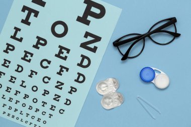 Mavi arka plan üzerinde kontakt lensler, gözlük ve aksesuarları ile düz yatıyordu kompozisyon. Vizyon konsepti.