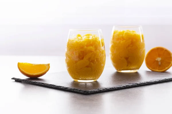 Fresh orange citrus sorbet garnished with mint - traditional cold dessert. Homemade fruit sorbet in a glass.