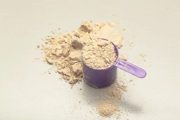 Chocolate whey protein powder with scoop on grey background
