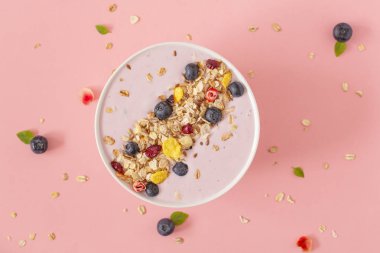 Pembe bir arka plan üzerinde nar, yaban mersini ve granola ile Smoothie kase. Lezzetli ve sağlıklı kahvaltı. Üstte görüntü. 