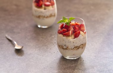 Granola, çilek, muz ve chia tohumu ile ev yapımı yoğurt parfait gözlük. Yoğurt, Chia, müsli ve taze çilek ile diyet tatlı. Sağlıklı kahvaltı 