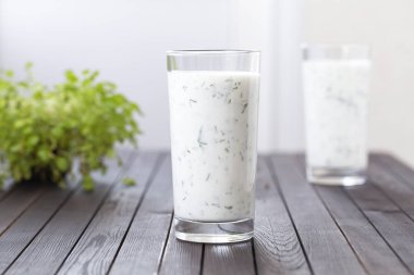 Taze ev yapımı yoğurt (kefir, ayran) otlar ile cam. Ayran, otlar ve salatalık ile ev yapımı yoğurt içecek - sağlıklı yaz serinletici soğuk içecek. Probiyotik fermente süt içeceği. Sağlıklı gıda. 
