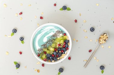 Sağlıklı kahvaltı. Mavi spirulina smoothie kase yaban mersini, kivi, Chia tohumu ve gri masada granola ile. Vegan gıda.