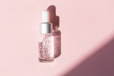 Pembe arka planda pipetli kozmetik veya tıbbi şişe. 