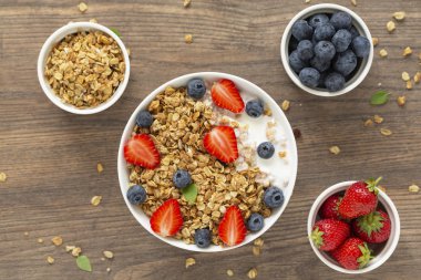 Ahşap arka plan üzerinde granola, yoğurt, çilek ve taze yaban mersini ile Sağlıklı smoothie kase. Kahvaltı smoothie kase, üst görünümü.