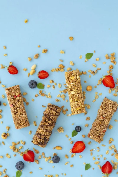 Granola bar. Healthy sweet dessert snack. Dietary food. Cereal granola bar with nuts, fruit and berries on a blue background. Top view, copy space.
