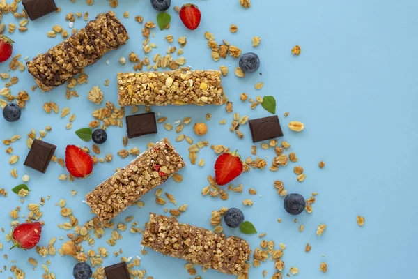 Granola bar. Healthy sweet dessert snack. Dietary food. Cereal granola bar with nuts, fruit and berries on a blue background. Top view, copy space.