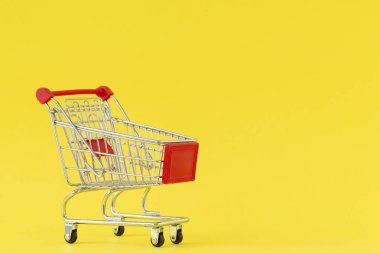 Alışveriş arabası. Sarı arka planda alışveriş arabası yakın çekim. Alışveriş kavramı. Kopyalama alanı.   