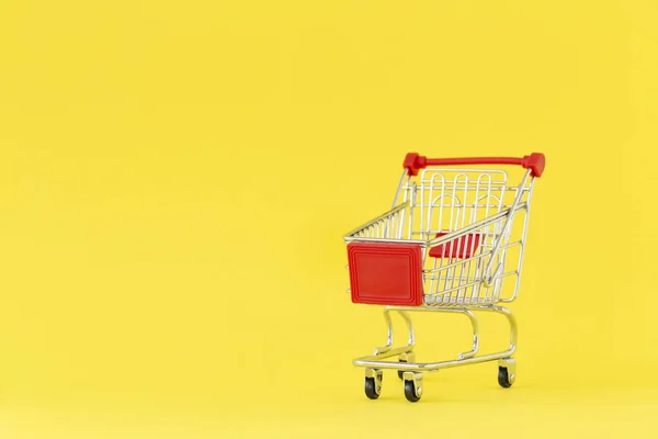 ショッピングカート 黄色の背景にショッピングトロリーのクローズアップ 買い物の概念 スペースのコピー — ストック写真